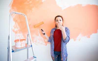 Beautiful female painting the wall with paint roller. Portrait of a young beautiful woman painting wall in her new apartment. Redecoration and renovation.